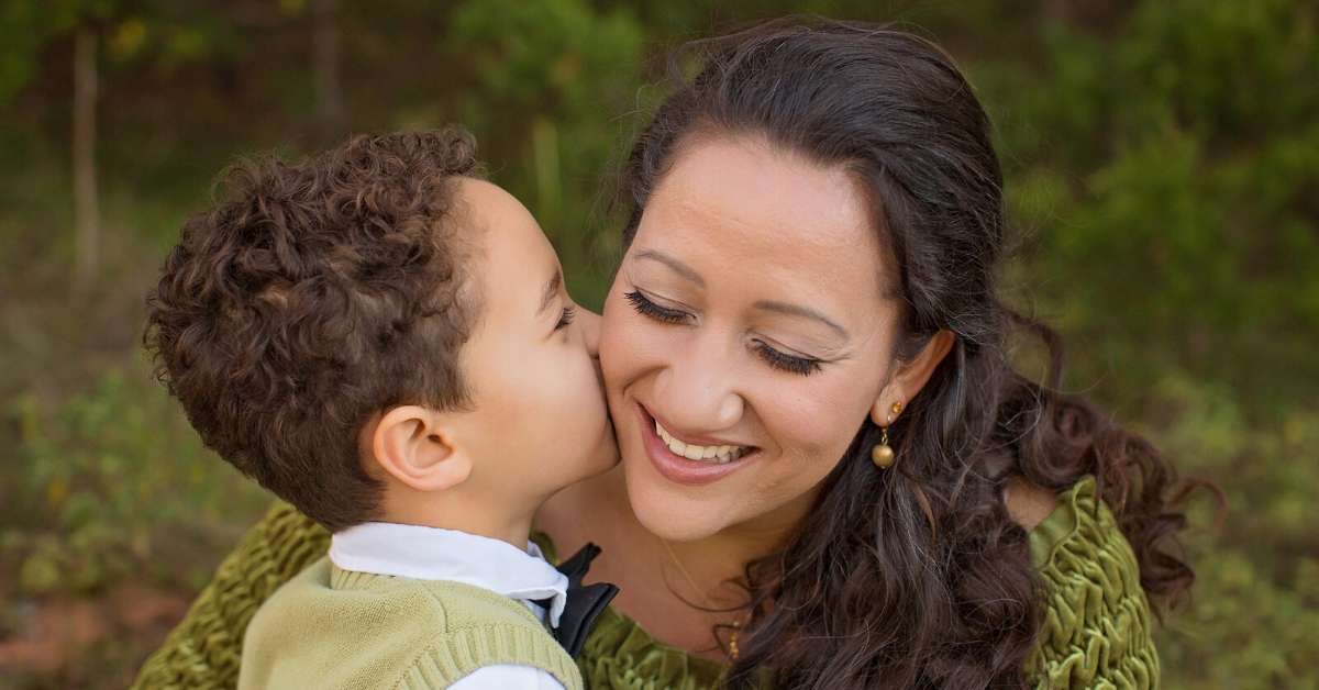 male child kissing adult female on the cheek